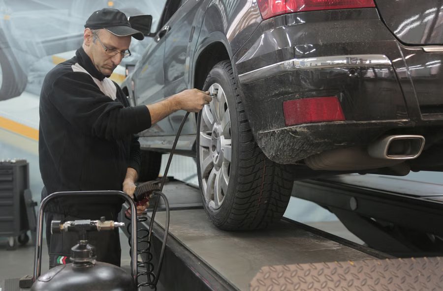 Mechanic using a tire inflation machine on a car lift